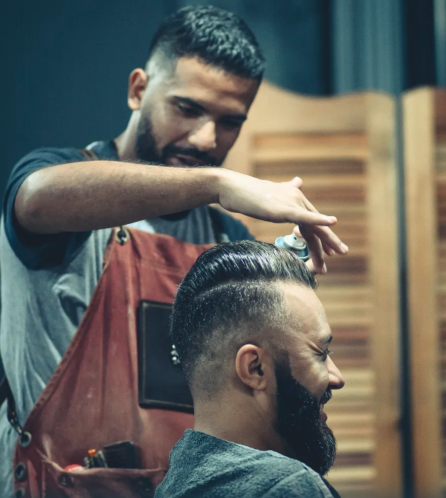 A stylist finishing a client's cut, comb in hand, in the chair.